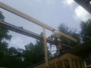 Carpenter setting a ridge beam over a new addition frame — Ice Dam Removal by Roofing Brothers in Thicket