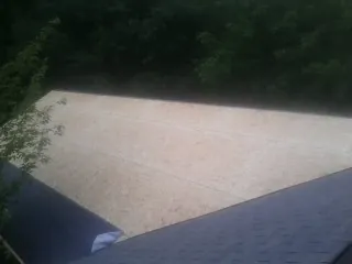 New OSB roof sheathing installed beside an existing shingle roof in Thicket