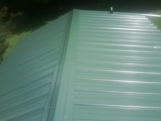 New green metal panels meeting at the ridge of a roof — Flat Roof Repair work by our crew in Thicket