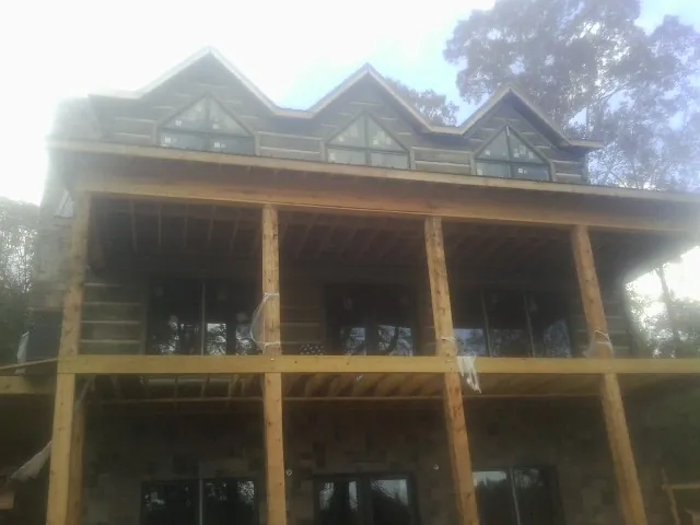 Dormers and porch framing on a large log home under construction — Roof Coating work by our crew in Thicket