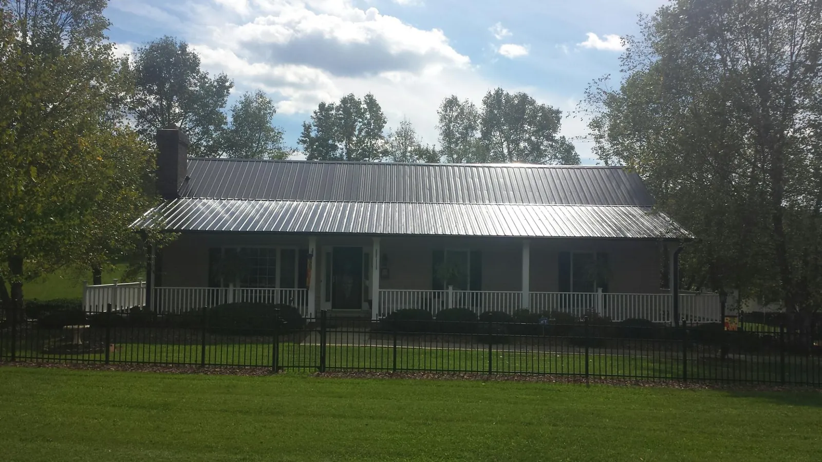 Gray metal roof on a brick ranch with a full width front porch — Gutter Guard Installation work by our crew in Thicket